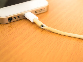 Closeup the Broken Smartphone Charger Cable with Smartphone Background
