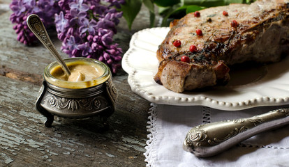 Fototapeta na wymiar Pork steak, mustard in a jar on the table. Vintage style.