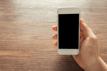 Cropped image of person showing mobile phone at desk