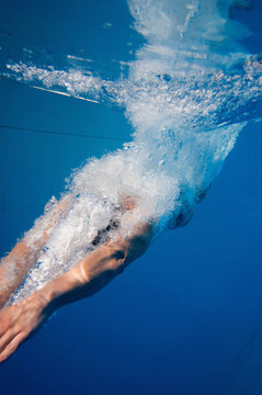 Young man dives into the pool, underwater shot