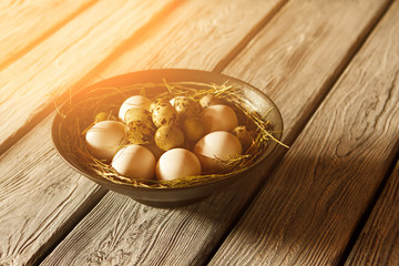 Bowl with whole chicken eggs. Uncooked eggs on straw. Product bought at local farm. Time to cook breakfast.