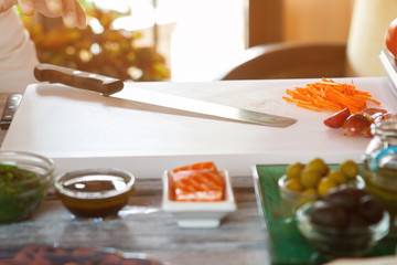 Knife lying on cooking board. Bits of shredded carrot. Cafe chef's workplace. Where did the master go.