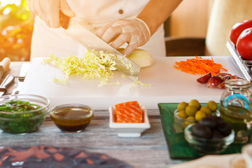 Hands with knife cut cabbage. Man preparing food at table. Chef makes tasty salad. Chinese cabbage is key ingredient.
