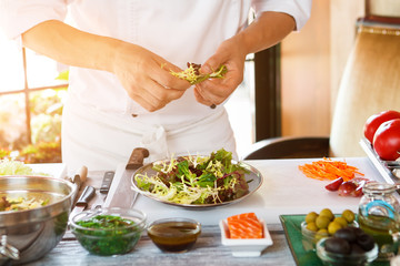 Man's hands holding herbs. Plate with salad. Chef's best recipe. Appetizer is almost ready.