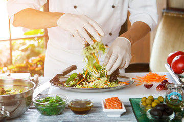 Male hands preparing salad. Bowls with olives on table. Let's mix it up. Special dish for regular customer.