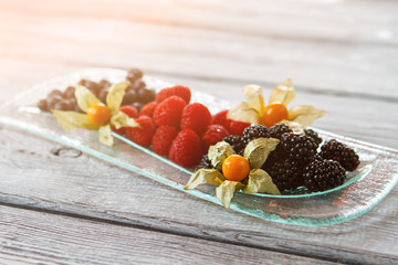 Raspberry and blackberry on plate. Plate with fruit dessert. Light dessert served at restaurant. Sweet taste of summer.
