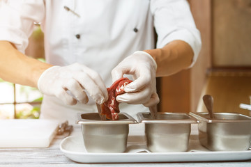 Man's hands holding meat. Sauce containers and raw meat. Chef starts preparing veal. Soak meat before cooking.