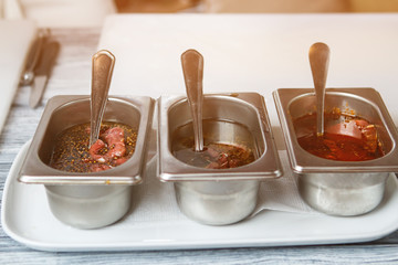 Pieces of meat in liquid. Containers with different liquid. Pieces of veal in sauce. Mustard with seeds.