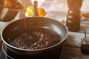 Liquid flowing onto frying pan. Dark liquid boiling on pan. Key ingredient for delicious sauce. Best sort of red wine. - obrazy, fototapety, plakaty