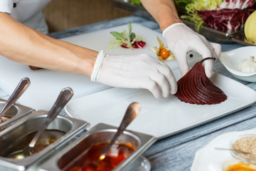 Men's hands touch cooked pear. Dark cooked pear on plate. Chef putting fruit on plate. Juicy and delicious.
