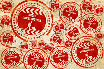Under construction sign, red stamp on a grunge paper texture