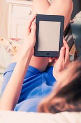 Close up of female hands holding e-book, lying on the couch