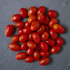 A pile of baby plum tomatoes on a slate background