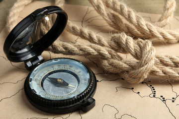 Fototapeta na wymiar the folded rope with an open compass lying on old map