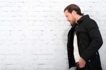 junger mann lehnt traurig an einer mauer
