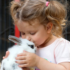 Baby girl kissing baby rabbit. © Vitalinka