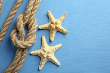 knot with different seashells on blue wooden background