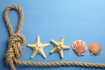 Fototapeta na wymiar knot with different seashells on blue wooden background