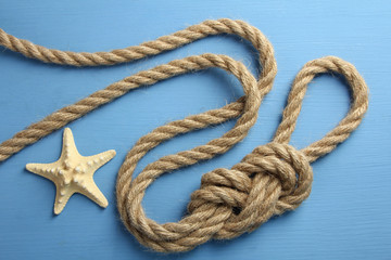 knot with different seashells on blue wooden background