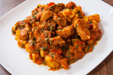Stewed meat with vegetables in a plate on wooden table