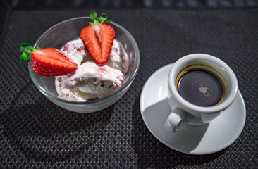 Strawberry dessert in glass plate and black coffee in white cup.
