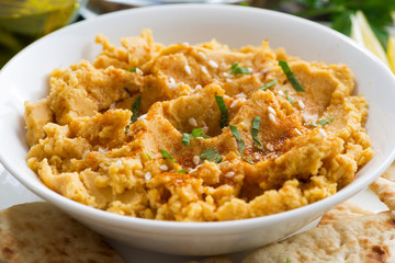bowl of Arabic sauce hummus with flatbread, closeup