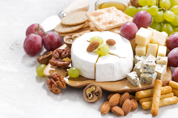 camembert, grapes and snacks on a white table, closeup
