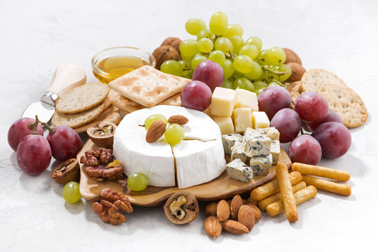camembert, grapes and snacks on a white background, closeup