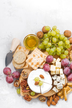 camembert, grapes and snacks on a white table, vertical