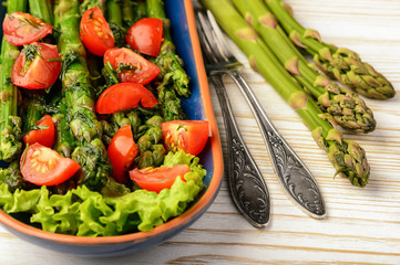 Appetizer - delicious vegetarian salad with green asparagus, tomatoes and vinaigrette dressing.