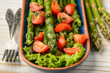 Appetizer - delicious vegetarian salad with green asparagus, tomatoes and vinaigrette dressing.