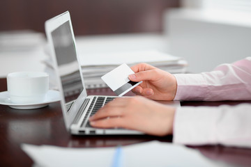 Close up of business woman hands using credit card and laptop computer