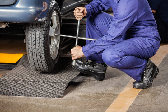 Mechanic Crouching While Fixing Car Tire