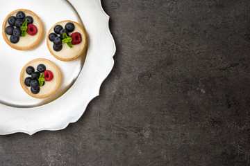 Delicious tartlets with raspberries and blueberries on a tray.
