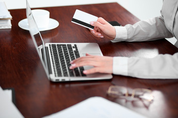 Close up of business woman hands using credit card and laptop computer