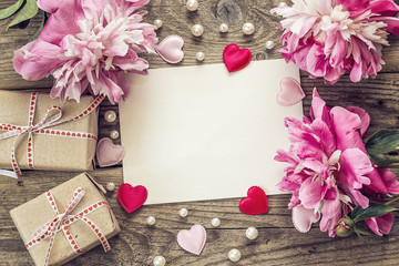 Purple peonies with a blank card, gift boxes and pearls on old w