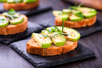Toast with avocado, herbs on slate board