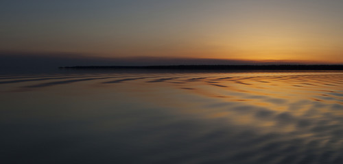 Rippling light across the water of a lake as the sun is below the horizon in saskatchewan canada