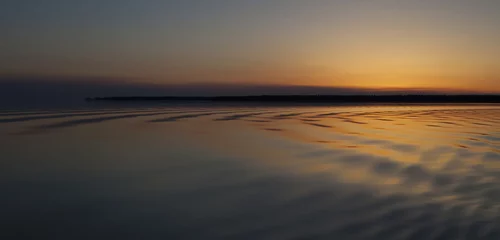 Foto op Plexiglas Rippling light across the water of a lake as the sun is below the horizon in saskatchewan canada © Guy Sagi