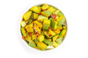Organic sliced Indian Mango (Mangifera indica), seasoned with turmeric, salt and red chili pepper in white bowl. Isolated on white background.Top view.