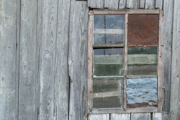 Natural lit vintage, old window in an ancient wooden weatherd grey wall in an abandoned farm barn, with room for copy space