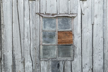 Natural lit vintage, old window in an ancient wooden weatherd grey wall in an abandoned farm barn, with room for copy space
