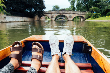 Man and woman feet on a boat punting in the river in  Cambridge. Focus on feet. © jjfarq