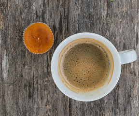 Cup of coffee and cupcake on a dark wooden background.