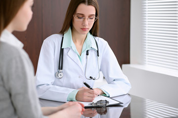 Doctor and  patient  sitting at the desk near the window in hospital