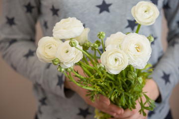 Closeup of woman's hands golding a bunch of beautiful white ranunculus. Grild with bouquet of flowers. Ranunculus. Holidays and lifestyle concept
