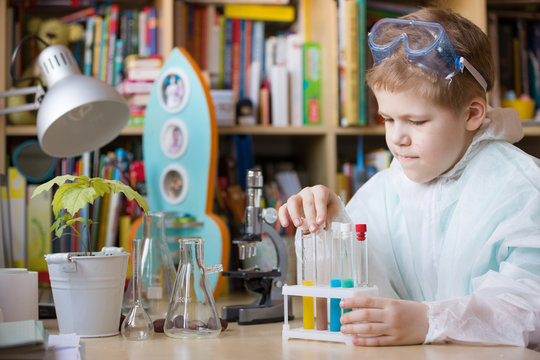 Cute School Kid Boy Sitting At The Table Making Science Experiments At Home. Learning Activities With Children At Home. Doing Water Tests. Future Profession - Scientist.