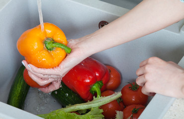 Woman hands washing paprika under the tap
