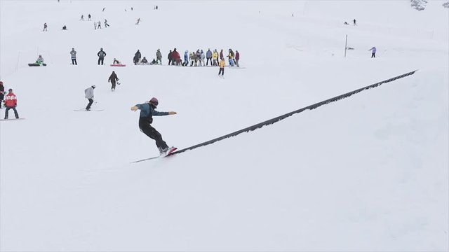Snowboarder ride on slope jump on trampoline in snowy mountain. Contest. Challenge. People. Slow motion