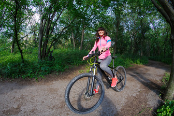Fototapeta na wymiar Young woman having fun riding a bicycle in the park.
